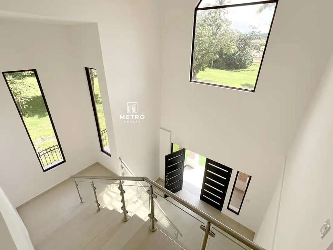 Entry foyer with modern staircase and glass railing in Clayton Forest Panama house