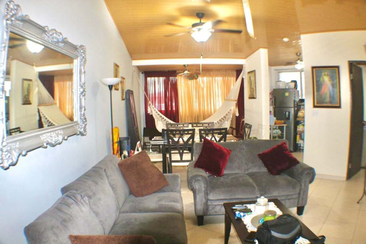 Open living and dining room with sofa, dining set, hammock in Llano Bonito Gardens apartment Panama City