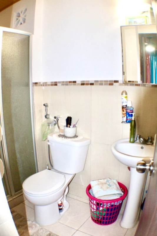 Small bathroom with glass shower enclosure and pedestal sink in Llano Bonito Gardens