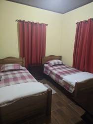 Twin bedroom with plaid linens, wood floors and curtains in furnished rental cabin Volcancito Boquete Panama
