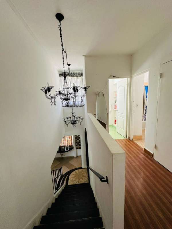 Bright hallway and curved staircase with wrought iron chandeliers in Balboa Ancón home