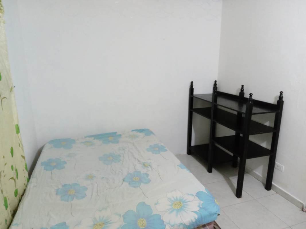 Bedroom with metal bed, floral curtain, and shelf in Parque Real residential complex