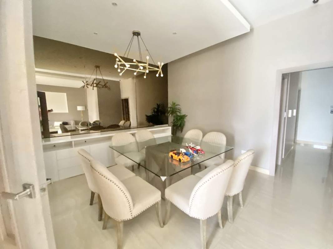 Elegant dining area with glass table, upholstered chairs, chandelier and mirror in remodeled El Dorado house Panama