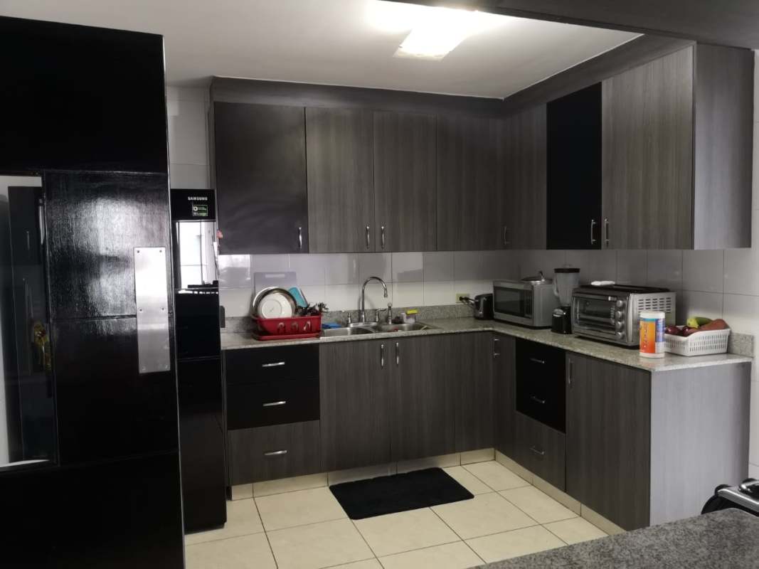 Modern kitchen with gray cabinets, granite countertops, black appliances at PH Parque Central Carrasquilla Panama