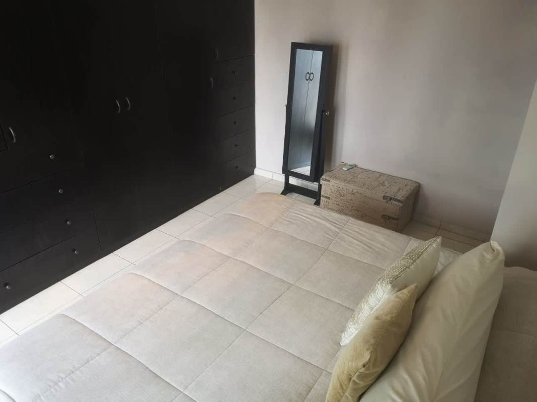 Minimalist bedroom design with black wardrobe, standing mirror and neutral tones in PH Parque Central Carrasquilla Panama