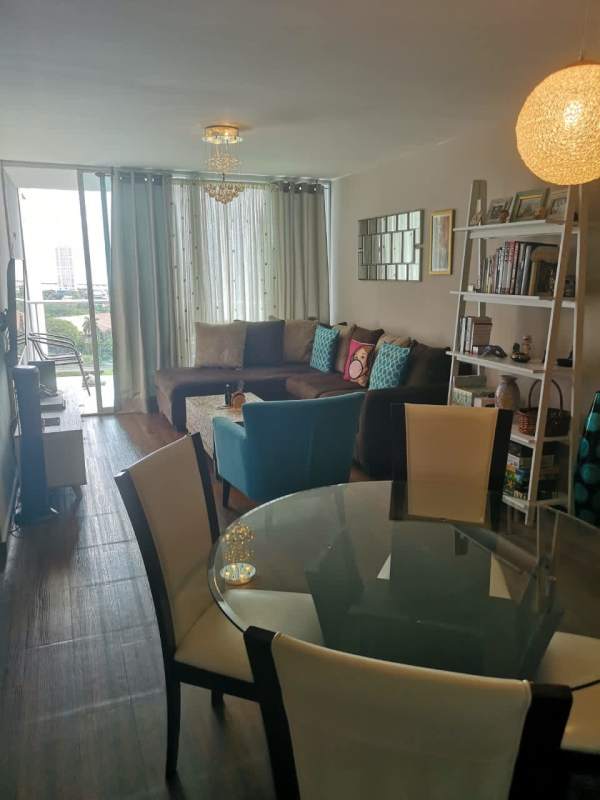 Modern living dining area with wood flooring, blue armchair, large windows overlooking city in PH Parque Central Panama