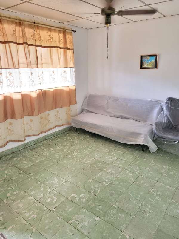 Modest living room with green tiles plastic covered sofa ceiling fan Ciudad Radial Panama