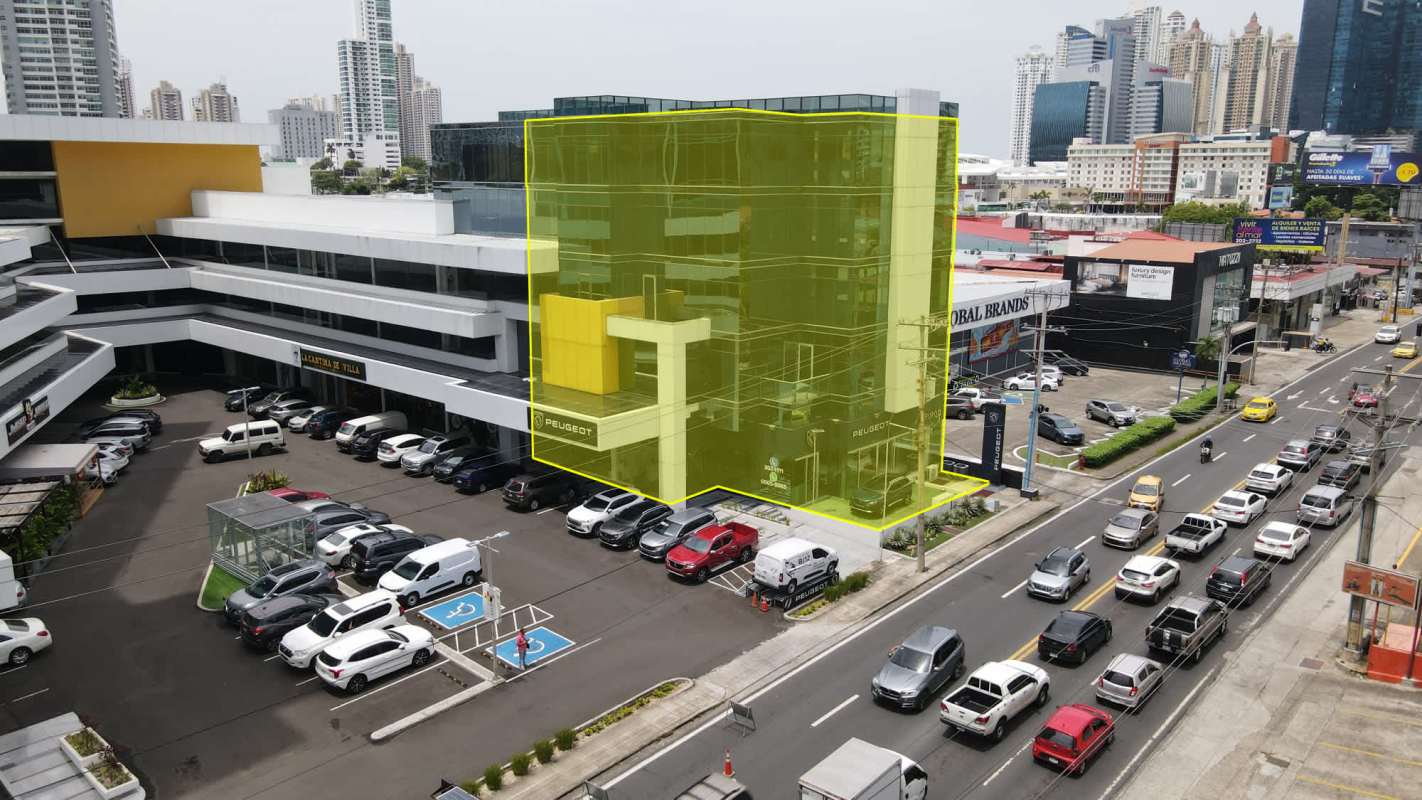 Aerial shot commercial building glass facade with large parking lot on busy Via Brasil, Panama City