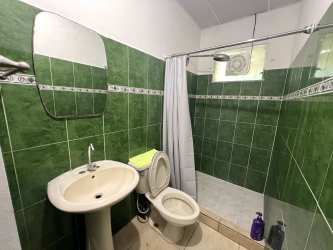 Rental house bathroom with green tiles, pedestal sink, and walk-in shower Residencial San Pablo David Panama