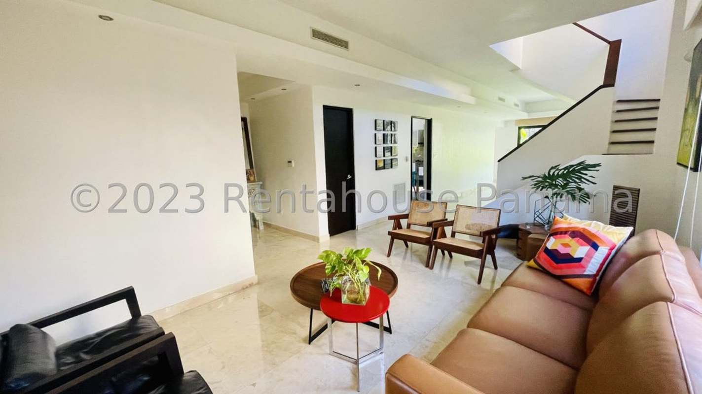 Spacious living room with marble floors, green accent wall, large sofa and work desk Clayton Panama City