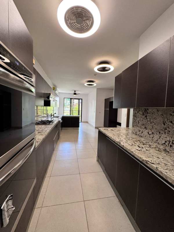 Modern kitchen with granite countertops, dark cabinets, built-in oven and appliances in Embassy Club Clayton
