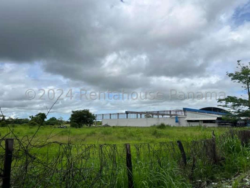 Fenced raw land beside industrial buildings with open field Pacora Panama