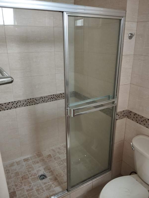 Small bathroom with glass shower enclosure and modern fixtures in Panama apartment