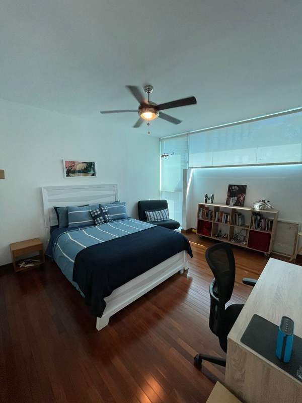 Elegant bedroom with built-in shelves, ceiling fan, wooden flooring, modern design at PH Bianco Loft Panama