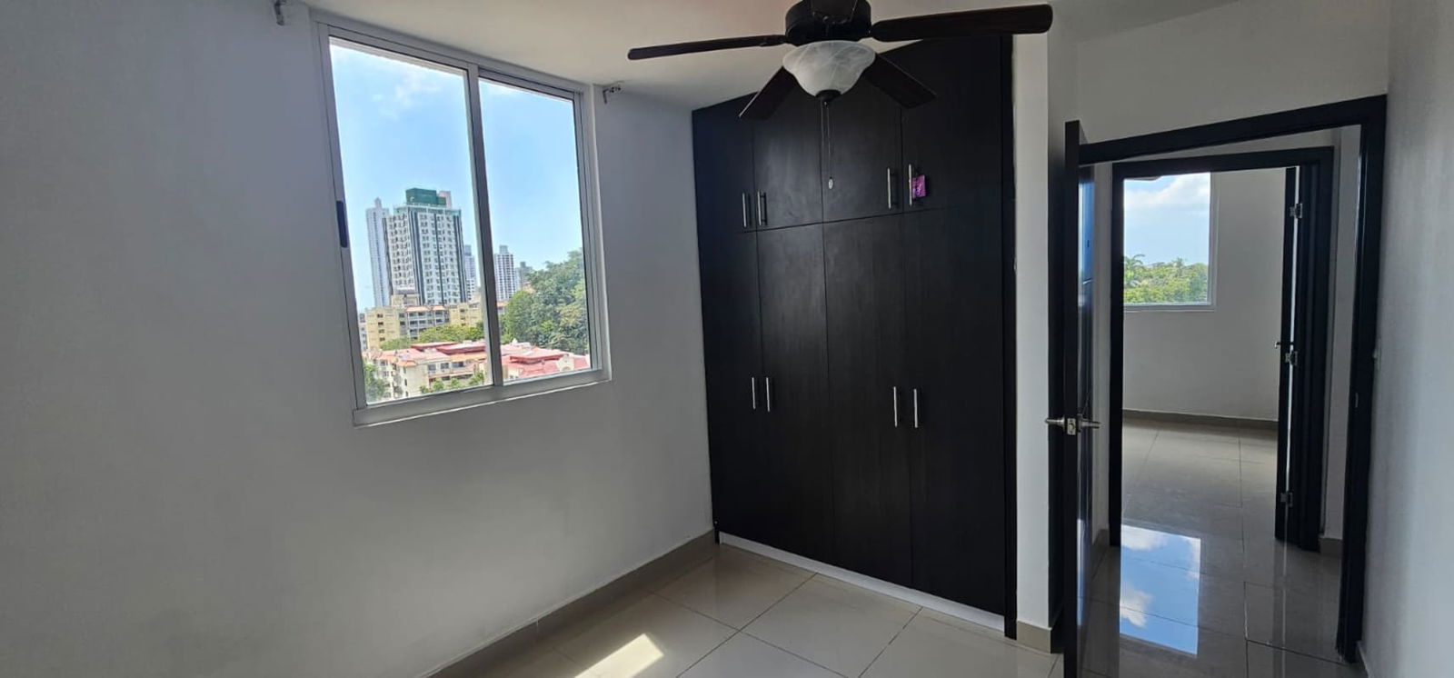 Bedroom with built-in wardrobe, large window and tiled flooring PH Park City Panama