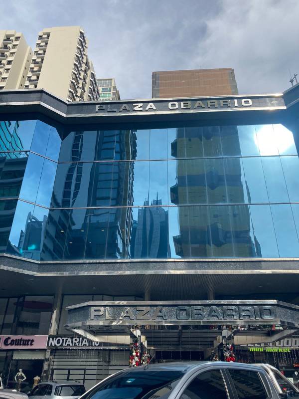 Facade of Plaza Obarrio commercial building with blue glass windows and retail ground floor Panama City
