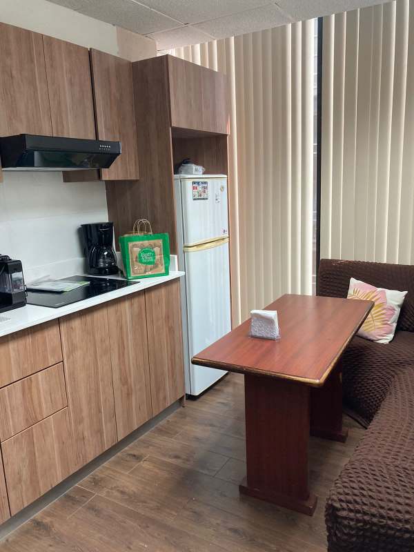Compact kitchenette with wooden cabinets, dining nook and sofa in PH Plaza Obarrio office building Panama