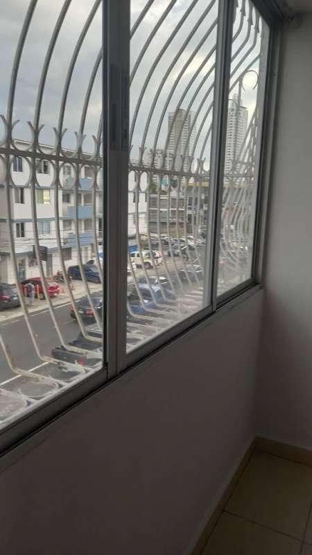 Enclosed balcony with glass sliding windows, metal security bars overlooking city street at PH Lefevre Residence Panama City