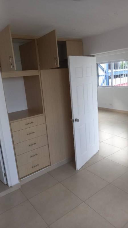 Second bedroom featuring built-in closet, white door, tile flooring, window with metal bars in Parque Lefevre Panama