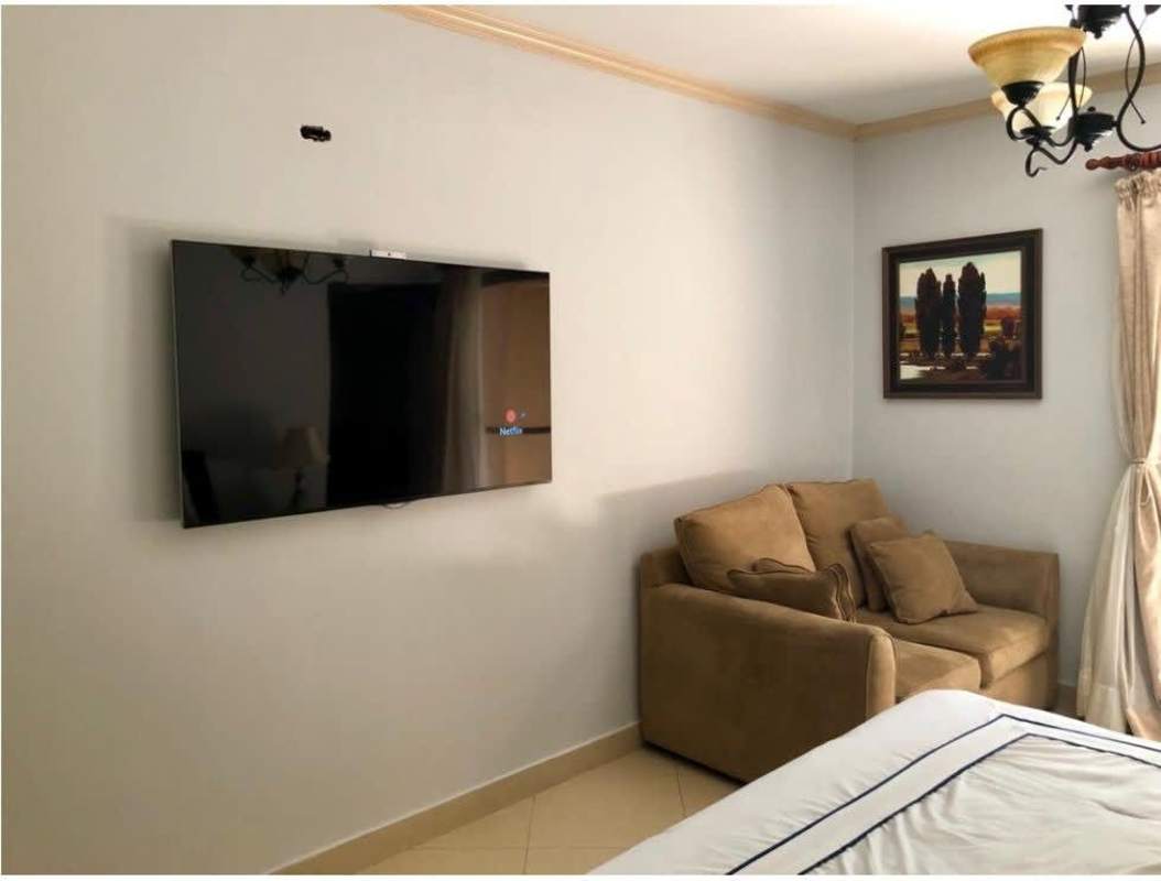 Contemporary bedroom with wall-mounted TV and beige armchair PH Clayton Park Clayton Panama