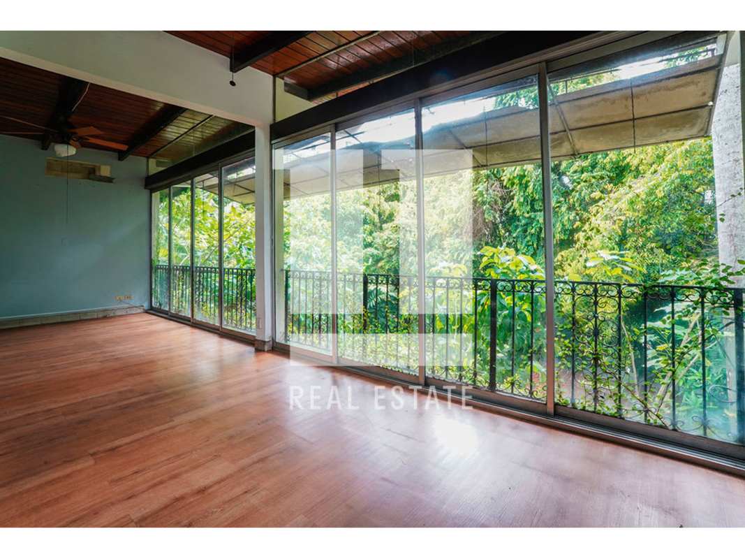 Bright sunroom or enclosed balcony with large windows overlooking garden Via Porras Panama