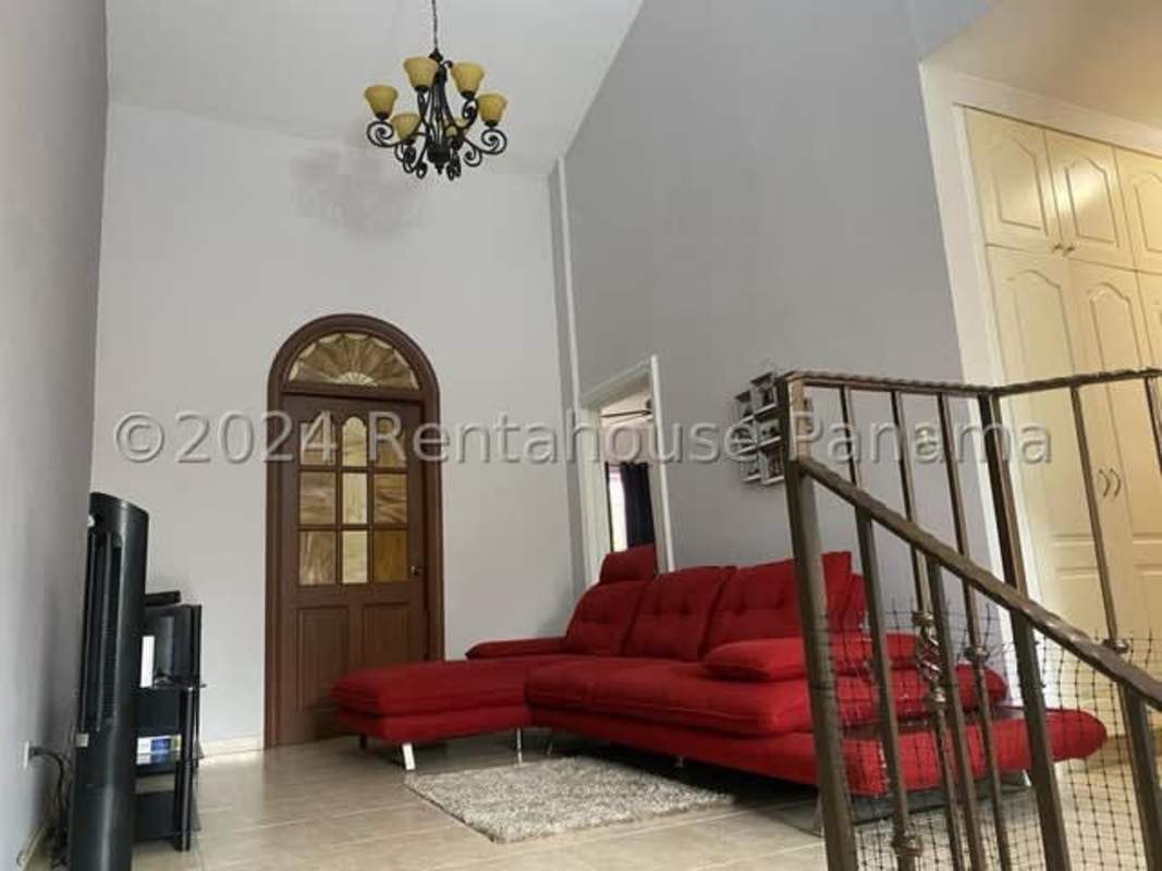 Living area with red sectional, arched door, high ceiling and chandelier in Costa del Este house Panama