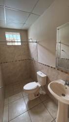 Simple second bathroom with ceramic wall tiles, pedestal sink, shower in rental house Arraijan