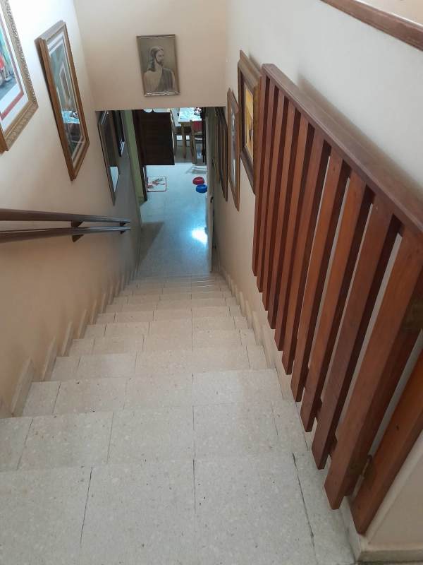 Indoor wooden staircase with traditional railing and dining area in La Alameda Panama house