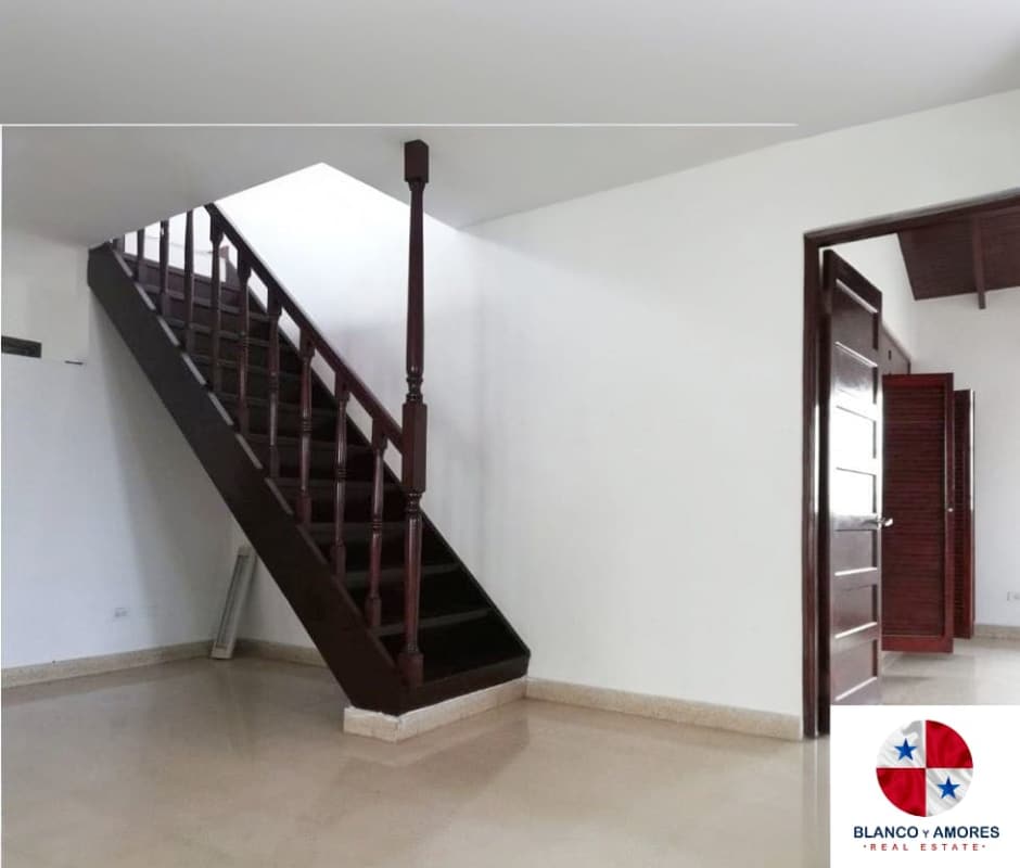 Interior with wooden staircase, tile floors, and white walls in two-level rental house El Dorado Panama