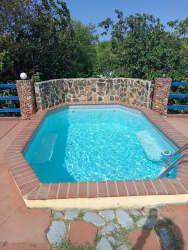 Outdoor swimming pool with natural stone wall and lush yard in San José Panama countryside home