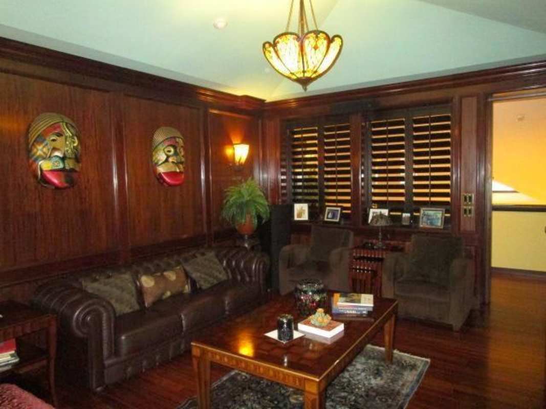 Traditional living room with wood paneling, leather sofa and art in Altos del Golf luxury house Panama