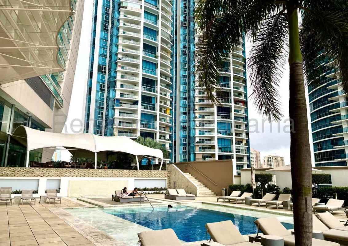 Luxury outdoor pool with sun loungers and palm trees overlooking ocean at Panama JW Marriott