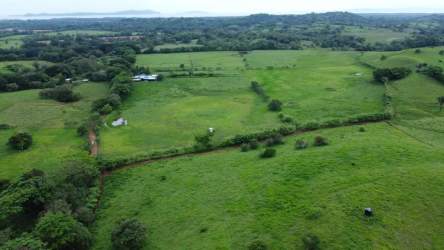 Wide aerial shot of farmland with pond and dirt road near Santiago