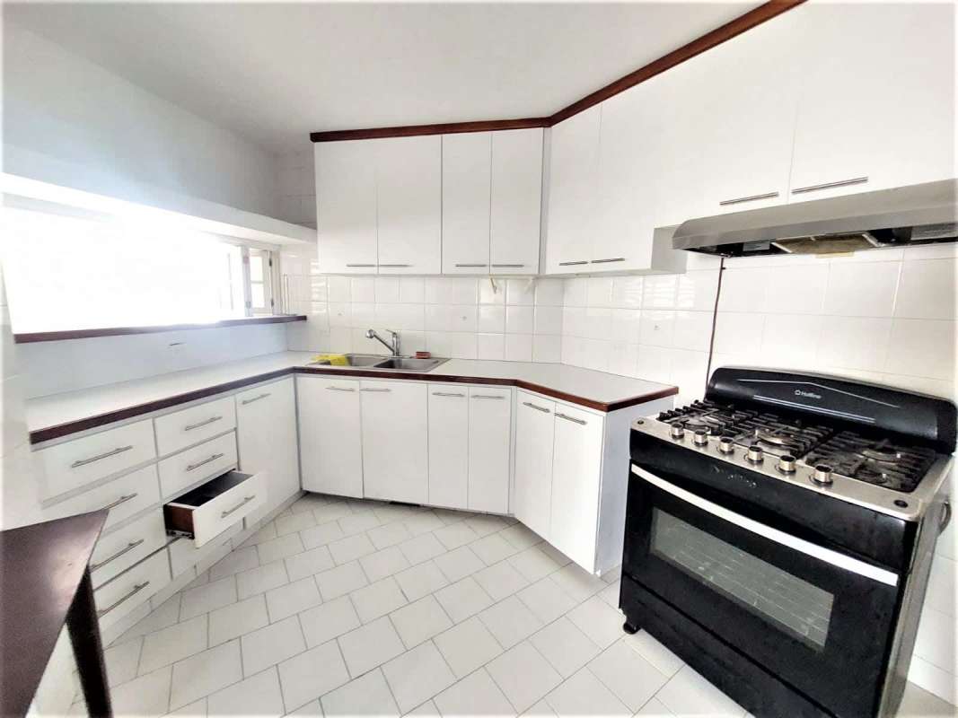 Fully equipped kitchen with L-shaped countertop, white cabinetry, and appliances in PH Coral Plaza Marbella Panama