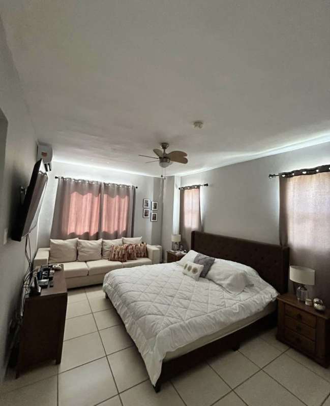 Contemporary master bedroom with large bed, sofa, ceiling fan, window blinds in PH Augusta Brisas del Golf Panama