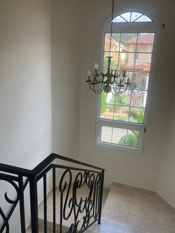 Indoor staircase with beige tiles and black iron railing leading to solid door duplex house Brisas del Golf Panama