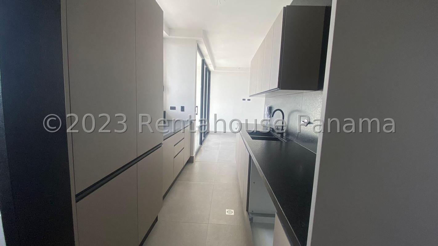 Sleek galley kitchen with black countertops and light cabinetry in Coco del Mar Panama