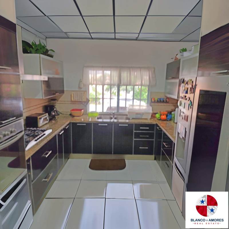 Contemporary gourmet kitchen with granite worktops, cabinetry, gas stove, large window in Altos de Panama home