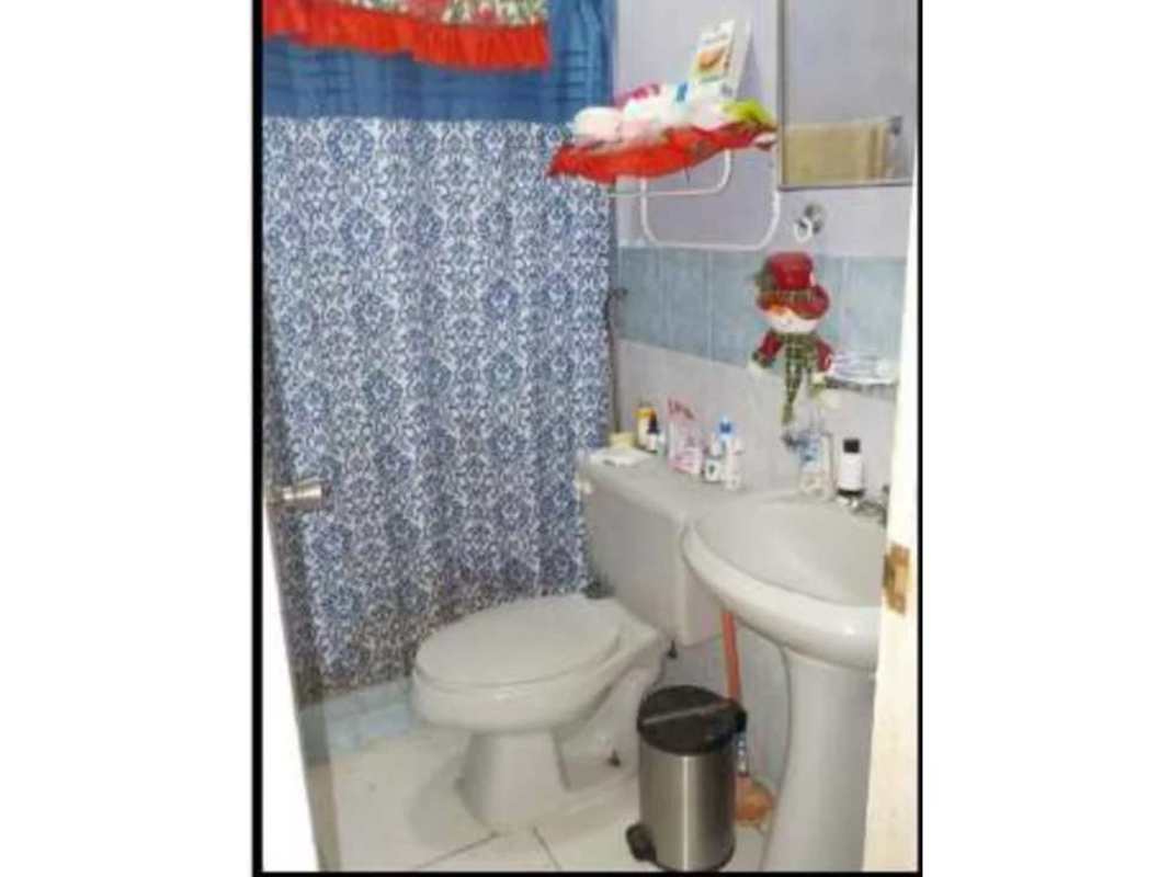 Small bathroom with blue shower curtain sink and wall shelf in Panama home