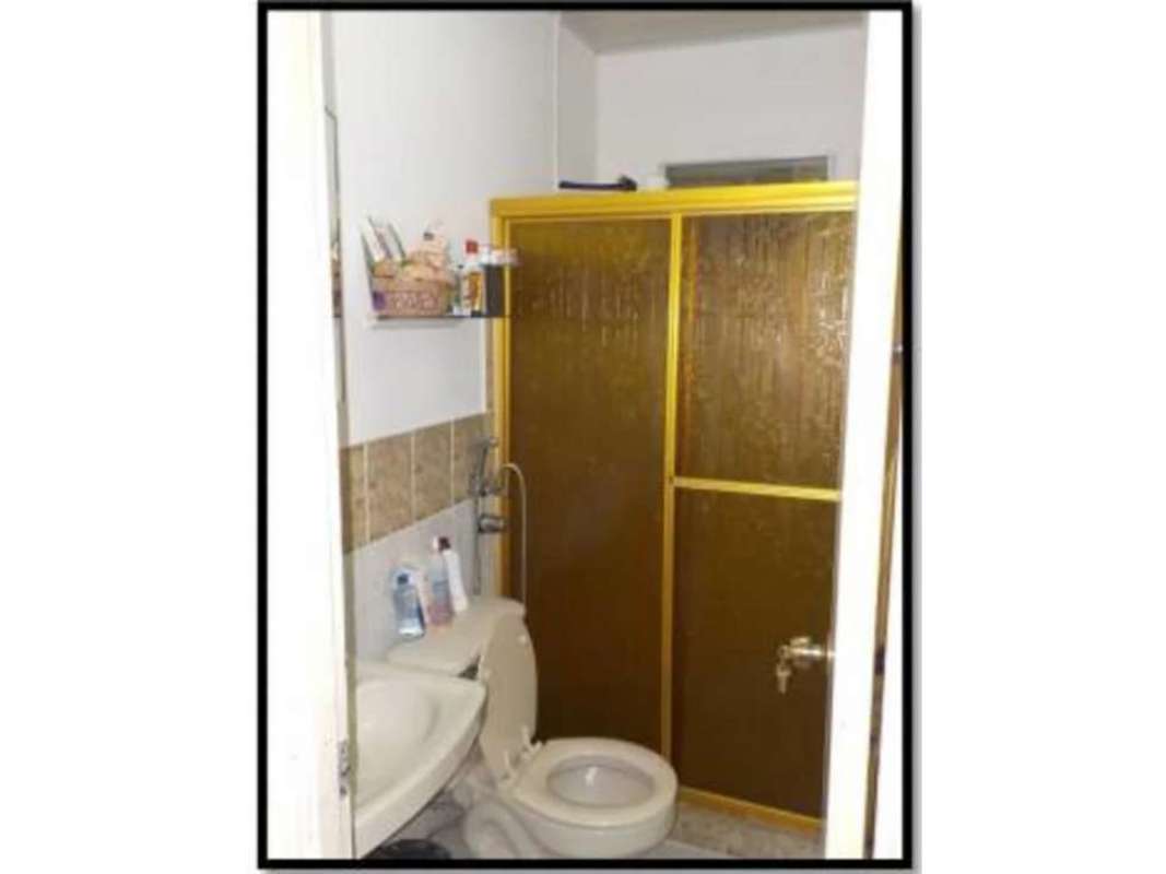 Bathroom with glass enclosed shower gold trim sink toilet Panama City house