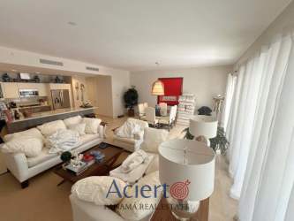 Open-plan living room with kitchen, comfortable sofas, dining table, bright windows in Buenaventura beach apartment Panama