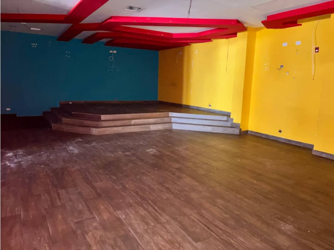 Interior commercial area with wood-look tile, raised platform, and colorful accents in Panama City