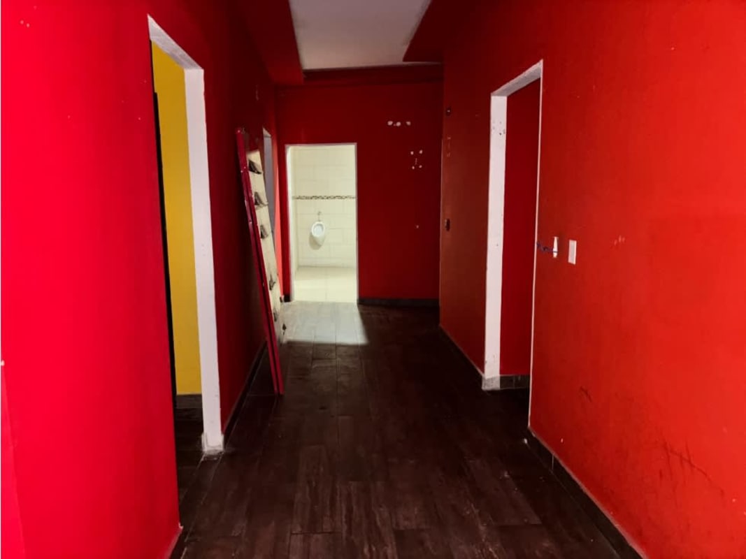 Colorful interior hallway with red walls, dark wood flooring leading to restrooms in commercial space Bella Vista Panama City