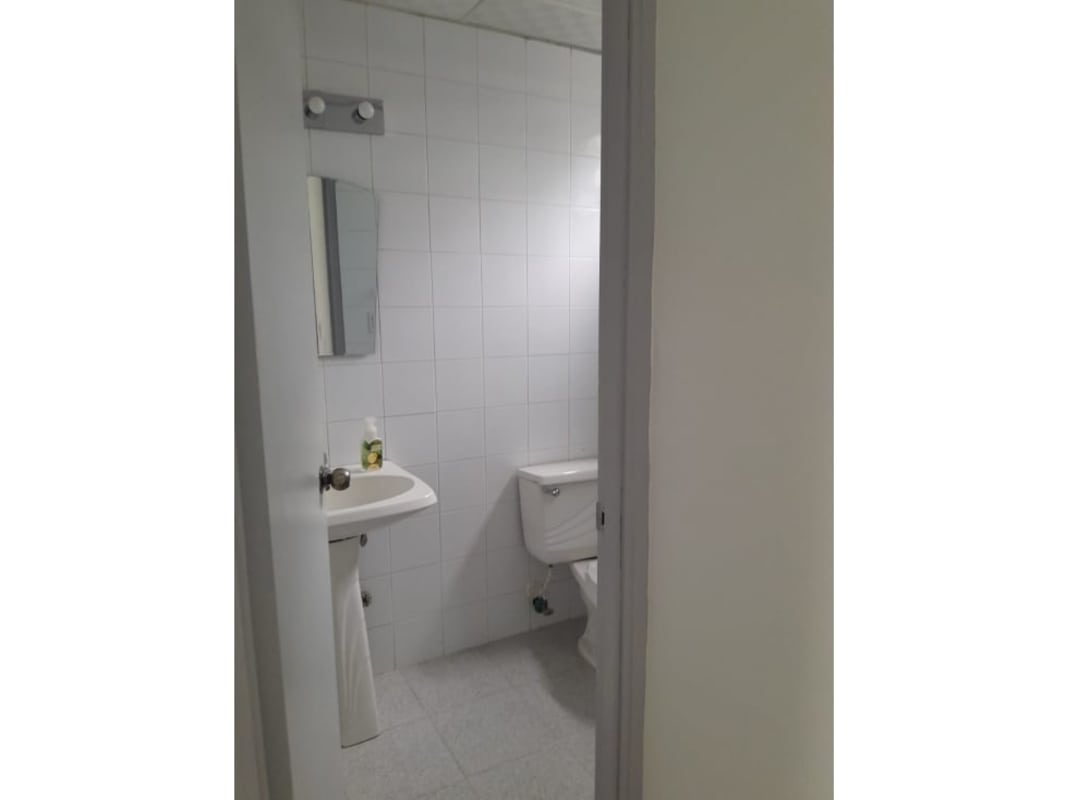 Private bathroom with white tile and fixtures inside commercial office Royal Center Marbella