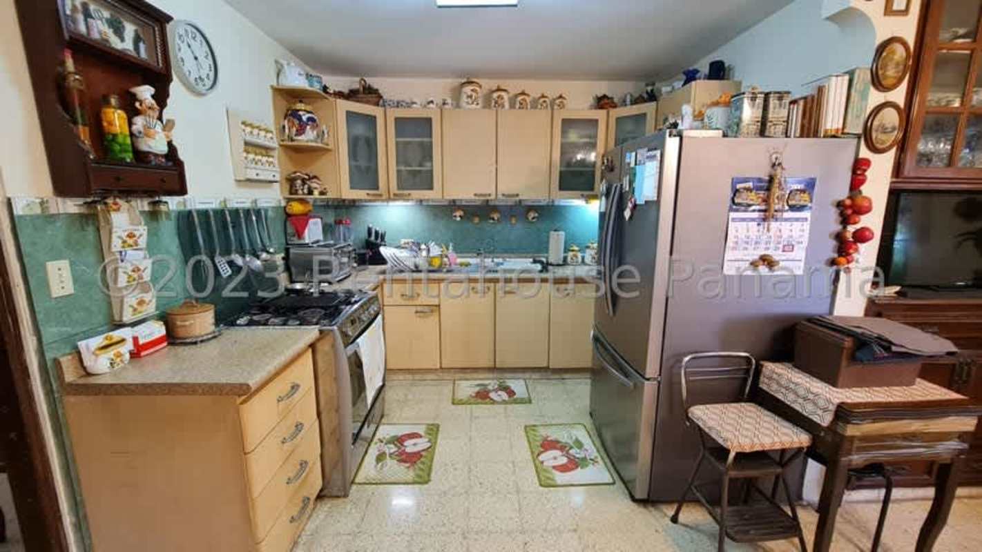 Traditional kitchen with L-shaped cabinetry, stove, fridge in Panama City house