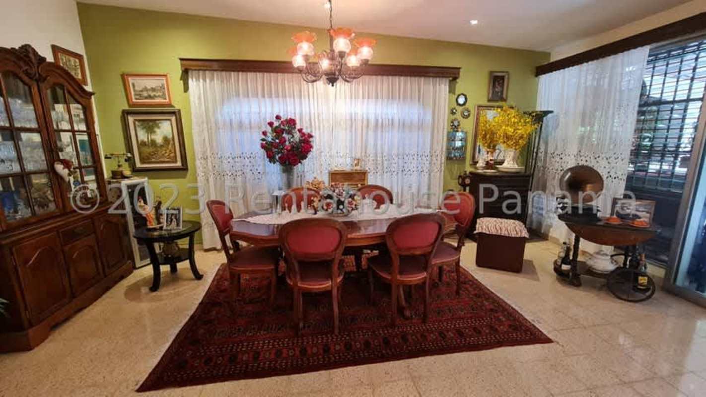 Dining room with chandelier, paintings, wooden furniture inside Hato Pintado house Panama