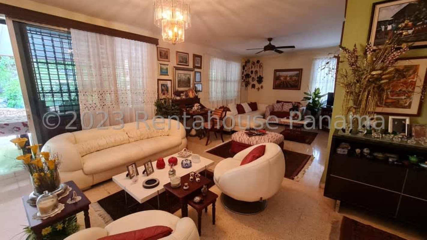Large living room with chandeliers, cream sofas, artwork and city views in house in Panama