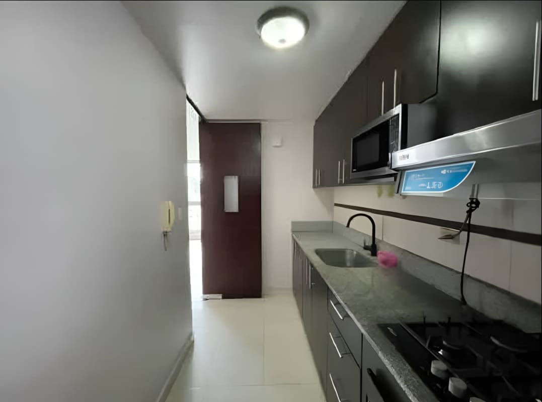 Apartment kitchen with granite tops, dark cabinets, microwave and gas stove in PH Villa de las Fuentes, Panama City