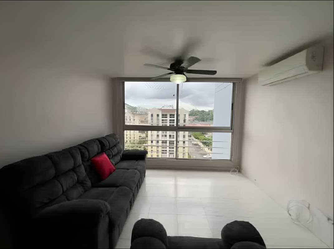 Modern living room with large window city view, black sofa, AC and ceiling fan at PH Villa de las Fuentes Tumba Muerto Panama City