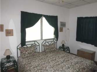 Traditional bedroom with floral bedspread, AC, curtains at Punta Barco beach house